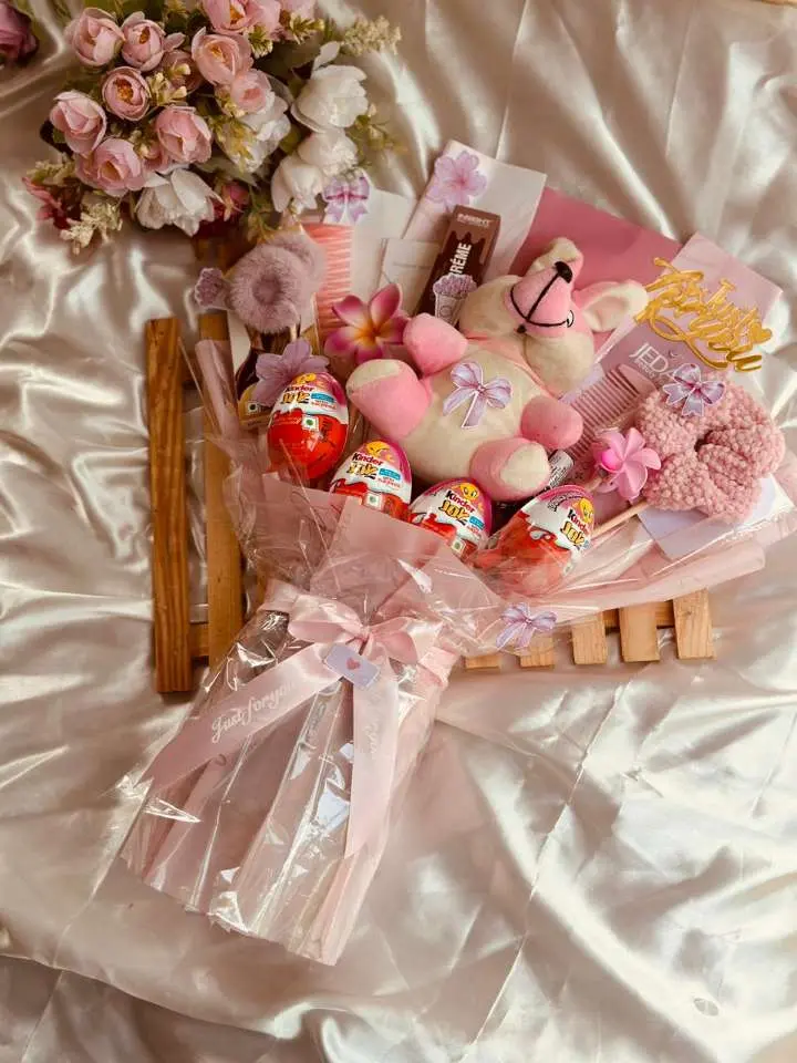 A cheerful arrangement of pink flowers with an assortment of cute stuffed animals nestled among them.